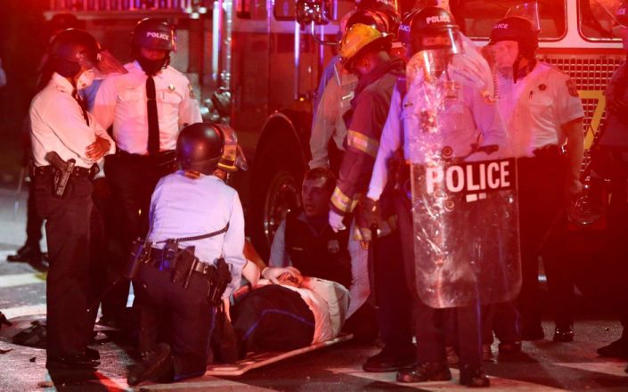A police officer lies on the ground before being loaded into an ambulance on 52nd Street in West Philadelphia - Tim Tai&nbsp;/The Philadelphia Inquirer&nbsp;