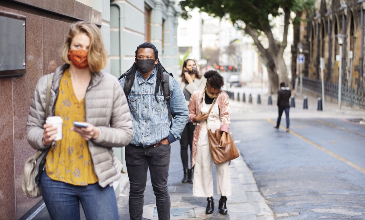 Group of diverse people in face masks social distancing on a city sidewalk